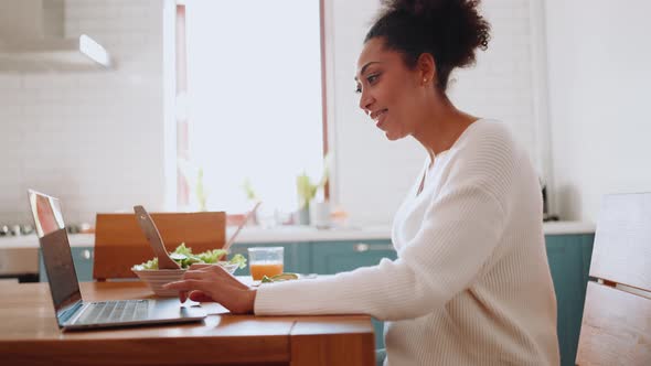 Positive African pregnant woman working on laptop