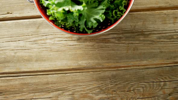 Green lettuce leaves in cooking pot placed on wooden table 