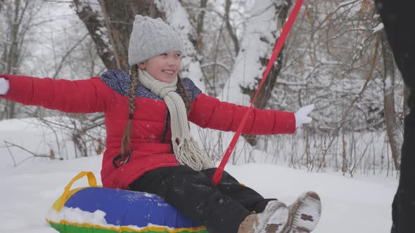 A Happy Girl Rolls on Tubing Along a White Snowy Road and Laughs in a Flight of Freedom. Christmas