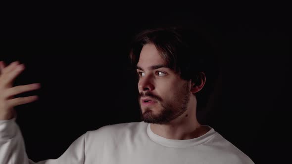 Trendy Young Man shooting finger gun at head, close, black background