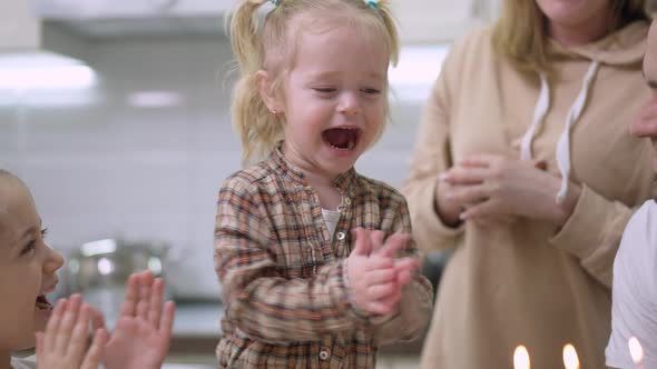 Portrait of Excited Baby Girl Clapping and Laughing Blowing Candles on Birthday Cake