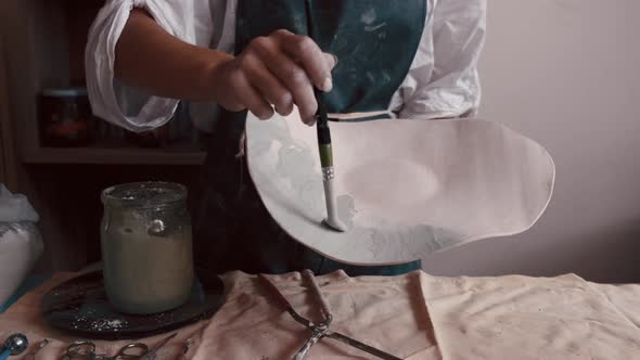 Professional Potter Decorating and Painting a Dish After She Has Baked It in the Kiln