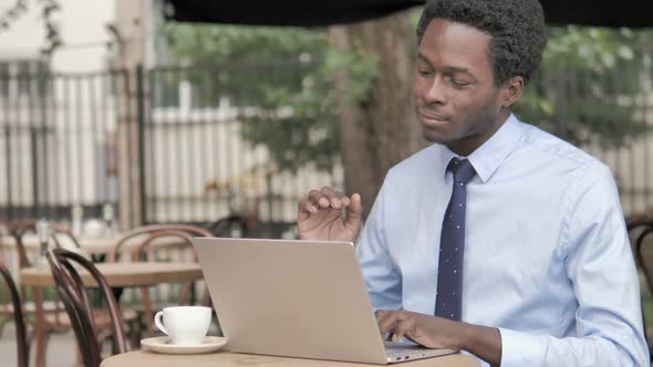 African Businessman with Neck Pain Using Laptop Outdoor