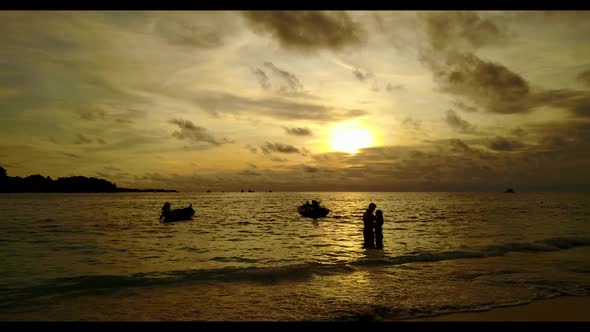 Romantic couple tanning on marine resort beach holiday by shallow sea with white sandy background of