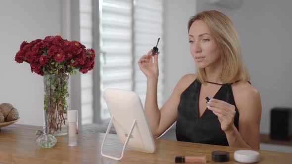 Beautiful Young Woman Applies Makeup. The Blonde Paints Her Face To Look Better