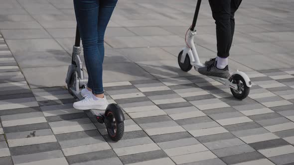 A Man and a Woman Ride Electric Scooters