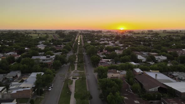 Dolly in flying over boulevard main street and Santa Elisa countryside town houses at sunset with br