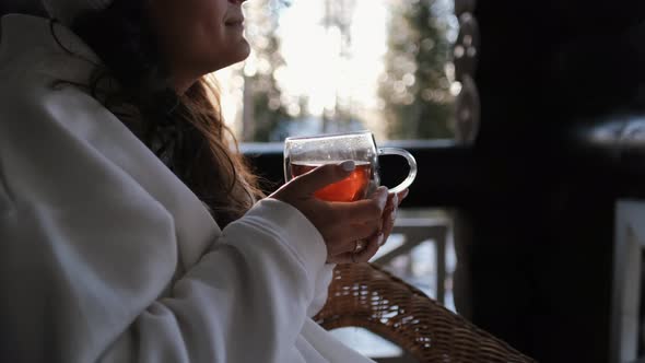 Attractive Young Woman in White Clothes Close-up Holds a Cup of Tea in Her Hands on the Balcony