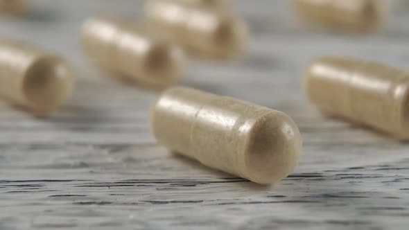 Beige herbal medical capsules on a wooden light background. 