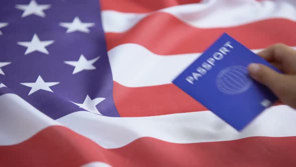 Female Hand Putting International Blue Passport on American Flag, Visa Applicant
