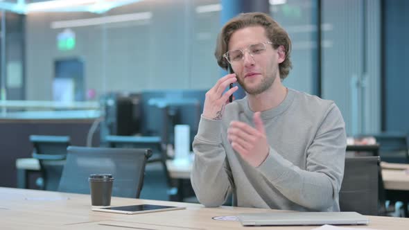 Young Businessman Talking on Smartphone in Office