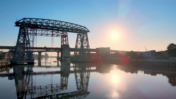 Low level aerial push out shot of ferry bridge Nicolas Avellaneda over the Matanza River during sunr