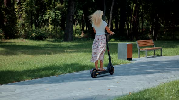 Woman Ride On Electric Scooter Mobility.E-Scooter Rider Rent Personal Eco Transport. Driving Ecology