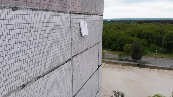 Aerial View on Styrofoam Block Feed on Rope To Industrial Climber Warming Facade