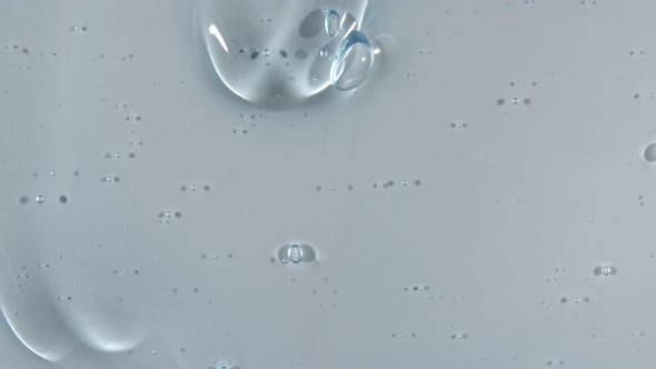 Transparent Blue Cosmetic Gel Fluid with Bubbles Flowing Down on a White Surface