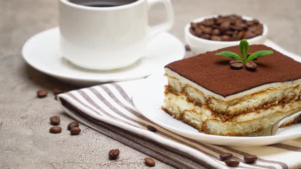 Portion of Traditional Italian Tiramisu dessert, cup of espresso and coffee beans