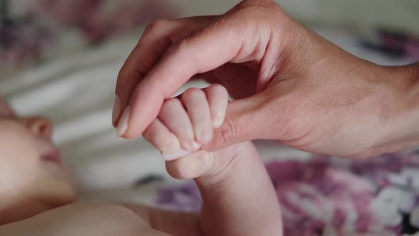Mom Holds the Hand of a Newborn