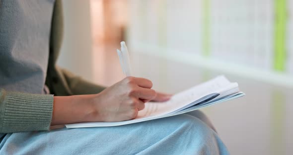 Woman writing on note at school