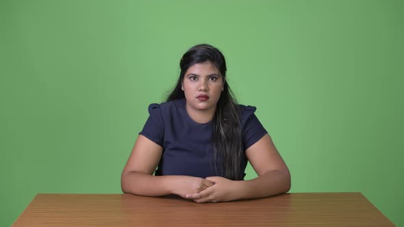 Young Overweight Beautiful Indian Businesswoman Against Green Background