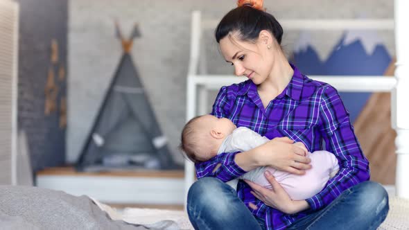 Happy Young Mother Holding Lovely Child and Kissing His Hand Medium Shot