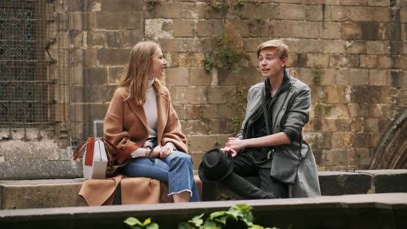 Boy and Girl Are Sitting Outdoor and Talking