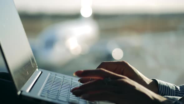 A Woman is Typing on a Keyboard While Waiting for the Flight