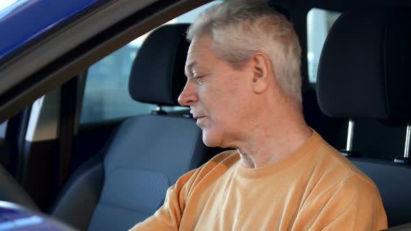 Senior Man Shows Car Key Through the Window