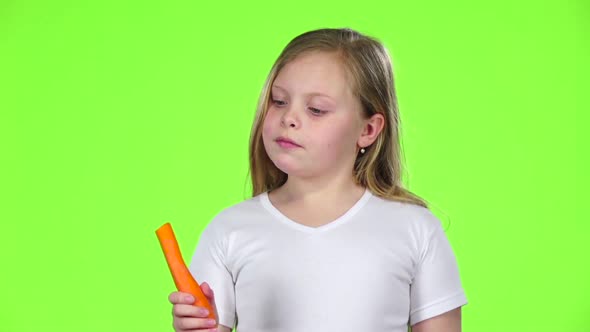 Little Girl Bites a Carrot, It Is Healthy. Green Screen. Slow Motion