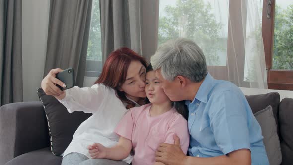 grandpa and grandma happy spend family time relax using mobile phone with young girl kid lying.