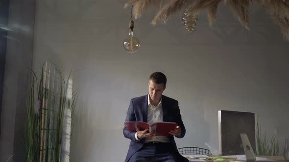 young businessman looks documents in a stylish office behind the glass