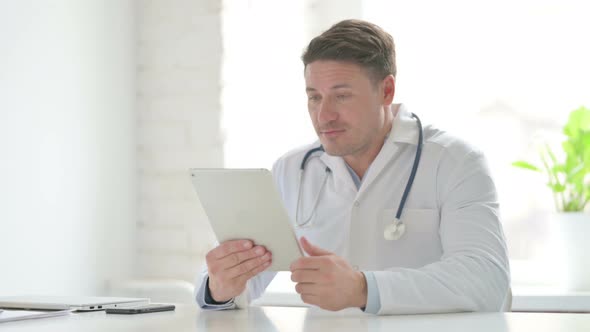 Male Doctor making Video Call on Tablet in Office