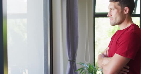 Thoughtful caucasian man with crossed arms looking at the window