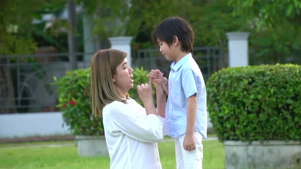 Asian Mother And Her Son Making A Pinkie Promise In The Park