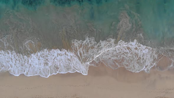 Waves crashing on Matadouro sandy beach. Aerial top-down lowering