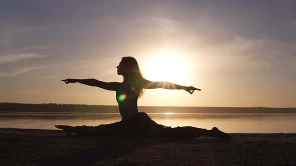 Beautiful Woman's Silhouette Doing Yoga Split on Sea Coast