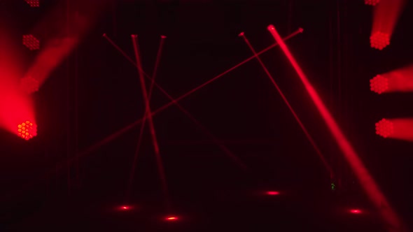 Bright Red Laser Lights and Spotlights Dynamically Rotate and Move Over Dark Stage