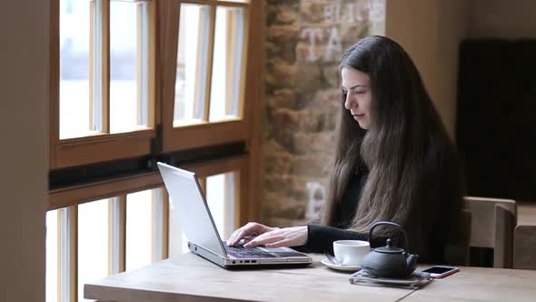 Woman working on laptop and smiling, business lady sitting in cafe