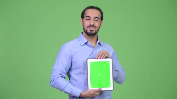 Young Happy Bearded Indian Businessman Thinking While Showing Digital Tablet