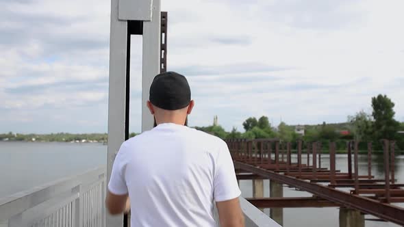 The camera follows the guy walking on the bridge