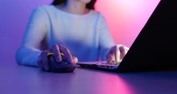 Woman use of notebook computer under red and purple light