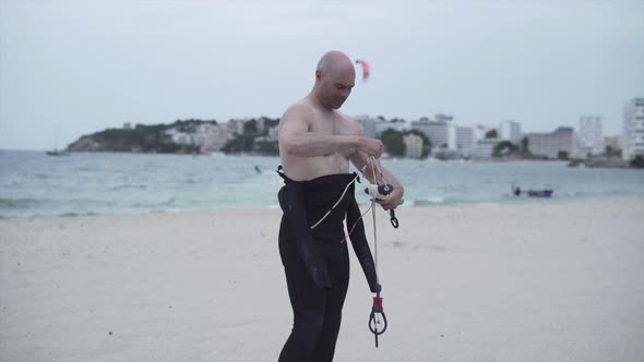 Masculine Man At The Beach Preparing Kite String For Kitesurfing In Mallorca Spain