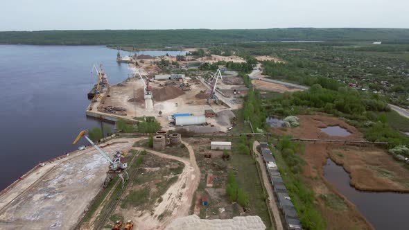 Large Harbor Cranes Onshore at the Quay Unload a River Gravel Barge Onto a Large Pile