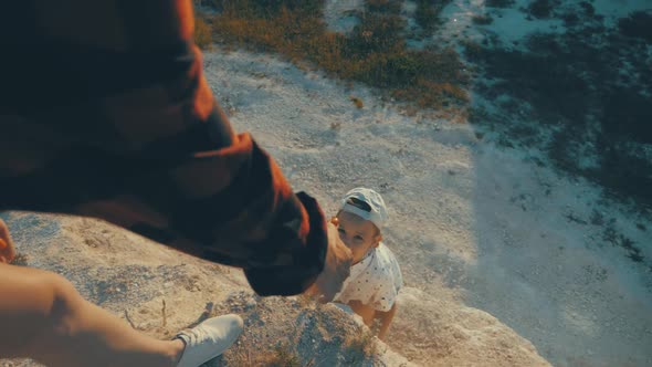 Girl Helps Her Friend Climb Up the Last Section of Mountain. Tourists with Backpacks Help Each Other