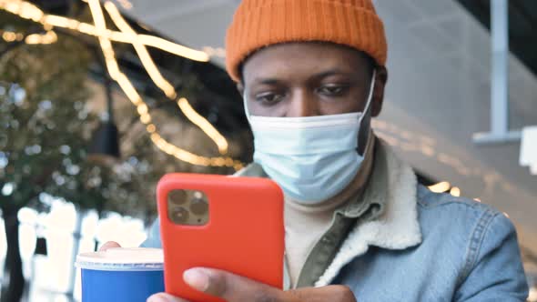Concentrated Black Guy in Mask Holds Smartphone and Types