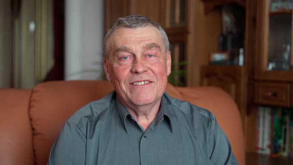 relaxed old retired single grandfather posing alone at home look at camera and smiling