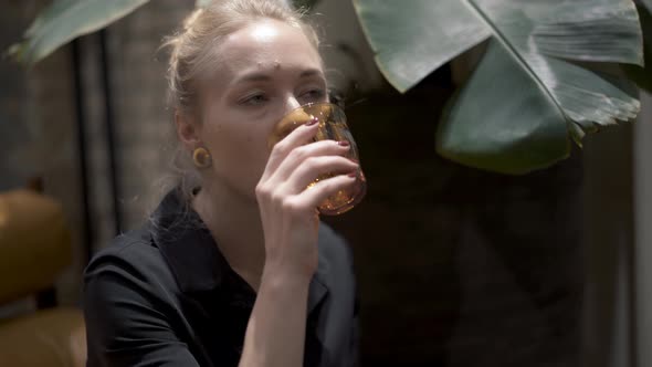 Handheld Close Up of Blonde Woman with Hair in a Bun Drinking Wine