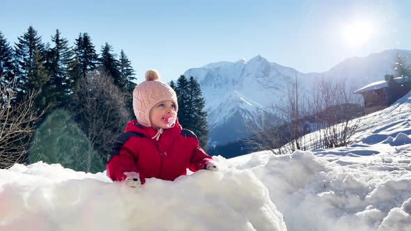 Little Girl Play in the Snow Fortress with Mountain on Back