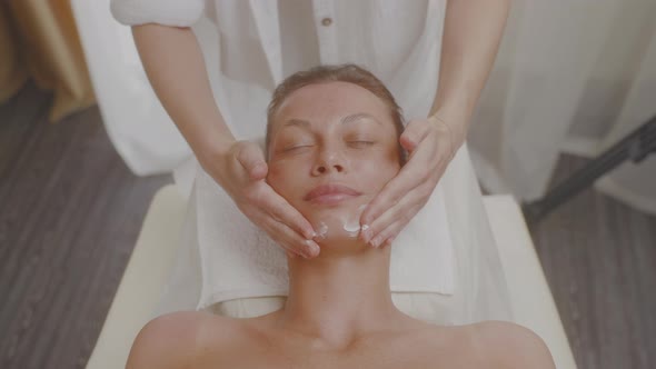 Cosmetologist Applies Moisturizing Cream to Skin of Face and Does Massage