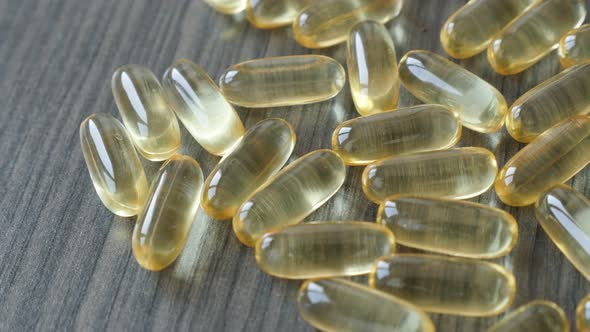 Cod liver oil medicines on wooden table slow pan 4K 2160p 30fps UltraHD footage - Soft gel capsules 