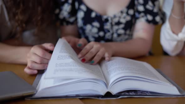 Three Students Reading Book Together in the Library Pointing on Text